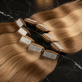 Tape-in hair extensions on dark marble surface